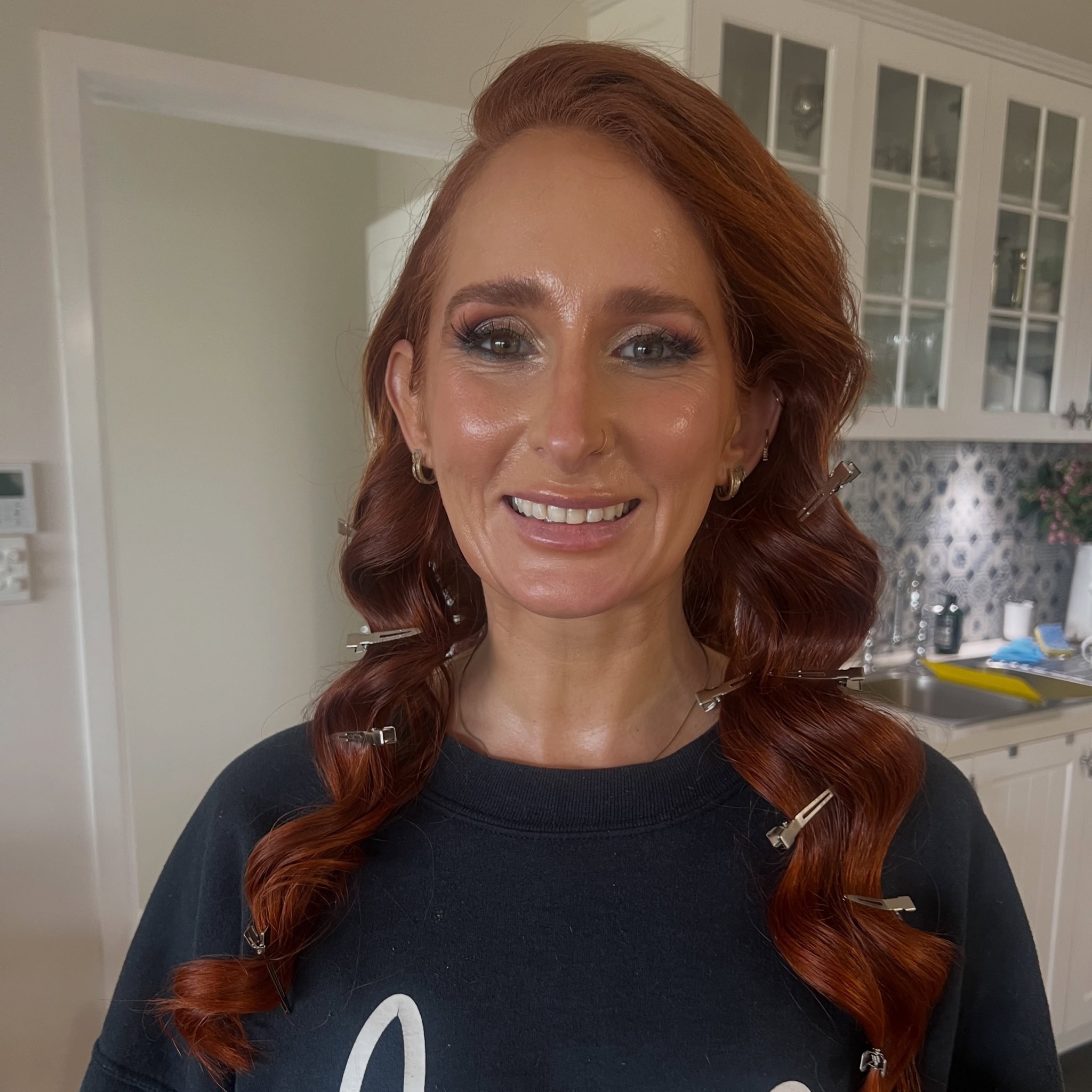 Glam curls and polished makeup on a red haired client