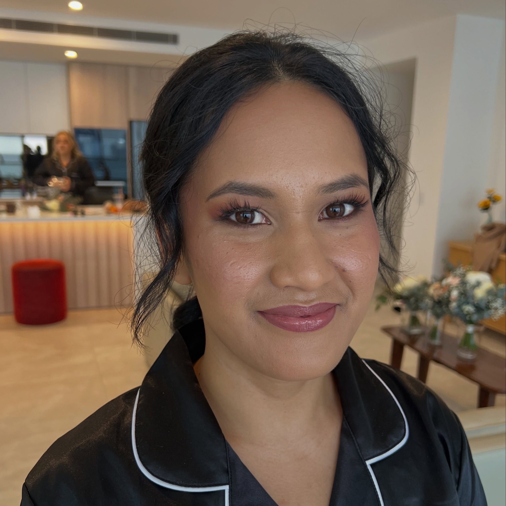 A bride in a black satin robe after her makeup, bridal suite behind